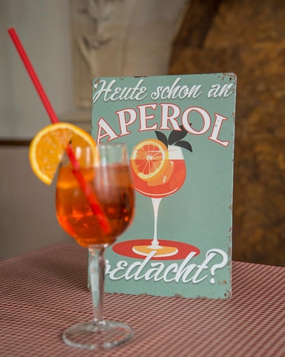 Blechschild mit Aperol Glas und Schriftzug Heute schon an Aperol gedacht in gemütlicher Szenerie