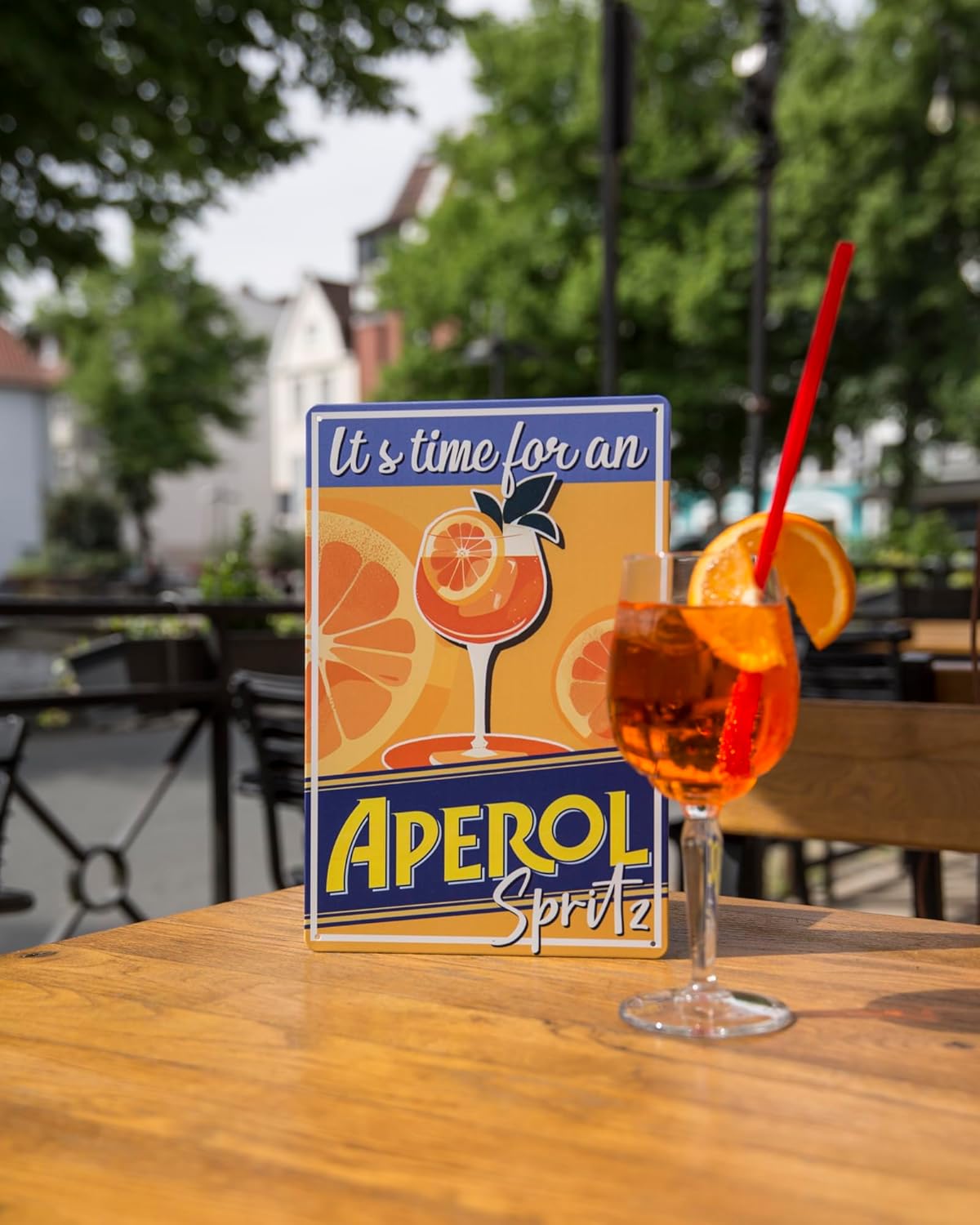 Blechschild mit Aperol Spritz Motiv in Außenbereich einer Bar